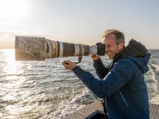 Photographer Ian Shive holds up his massive camera and lens on a boat to try and photograph the native Texas Whooping Crane in Aransas National Wildlife Refuge, Texas. These cranes travel over 2,5000 miles each year to winter in Texas on the 115,000 acre refuge.